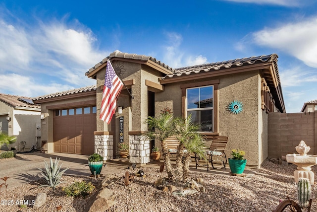 mediterranean / spanish house with fence, an attached garage, stucco siding, concrete driveway, and a tiled roof