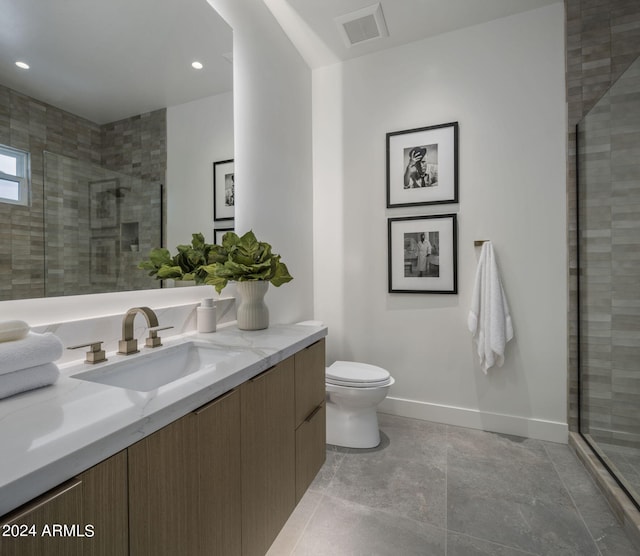 bathroom featuring a shower with door, tile flooring, toilet, and vanity