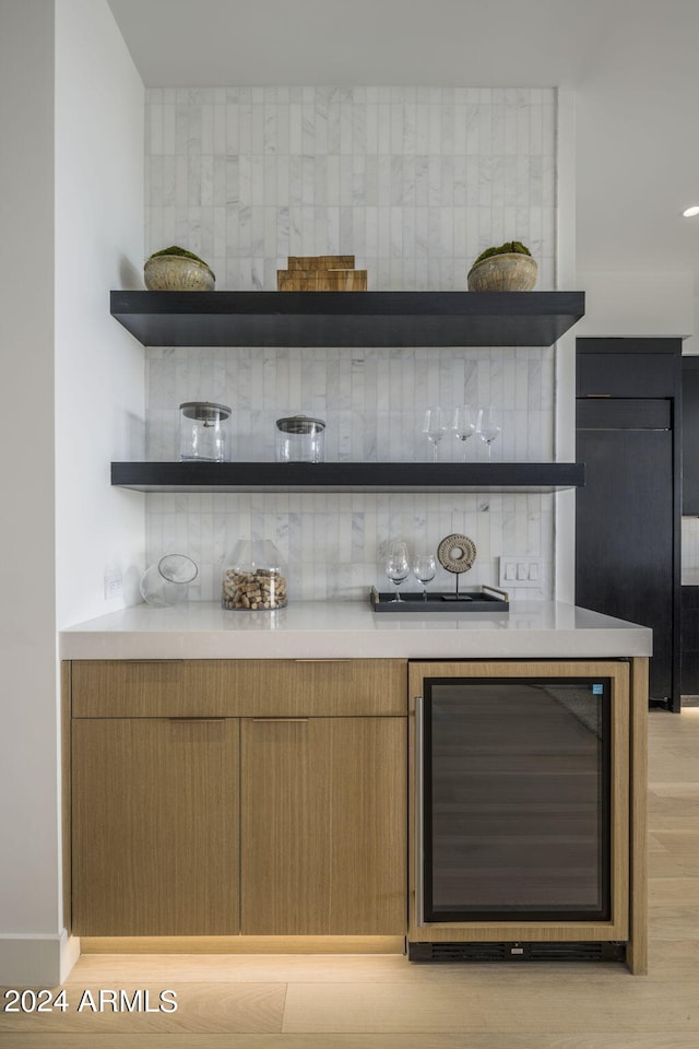 bar featuring backsplash, wine cooler, and light hardwood / wood-style flooring