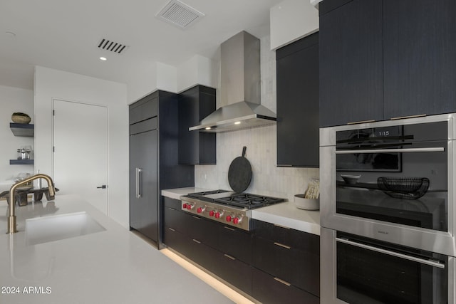 kitchen featuring stainless steel appliances, sink, wall chimney exhaust hood, and tasteful backsplash