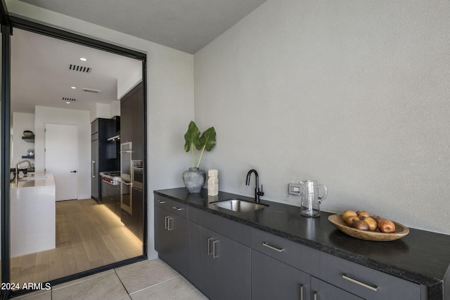 interior space with oven, sink, and light tile flooring