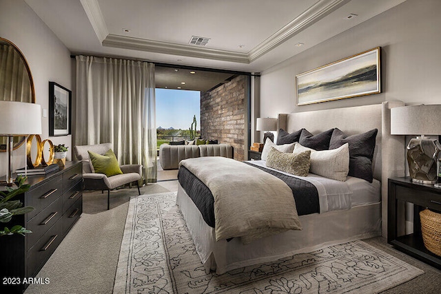 carpeted bedroom with a tray ceiling and brick wall