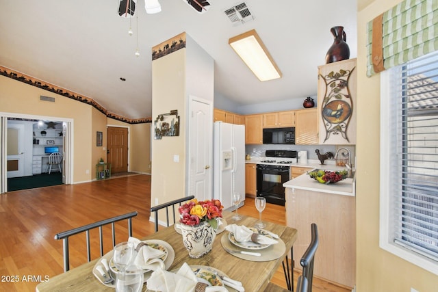 dining area with light wood-type flooring, vaulted ceiling, sink, and ceiling fan