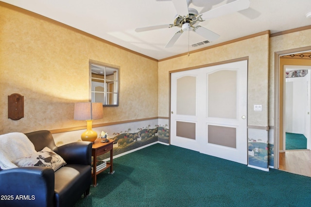 sitting room with ceiling fan, ornamental molding, and carpet floors