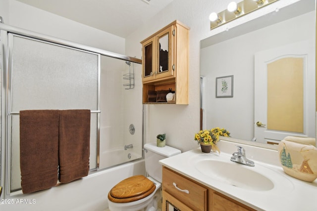 full bathroom with toilet, bath / shower combo with glass door, and vanity