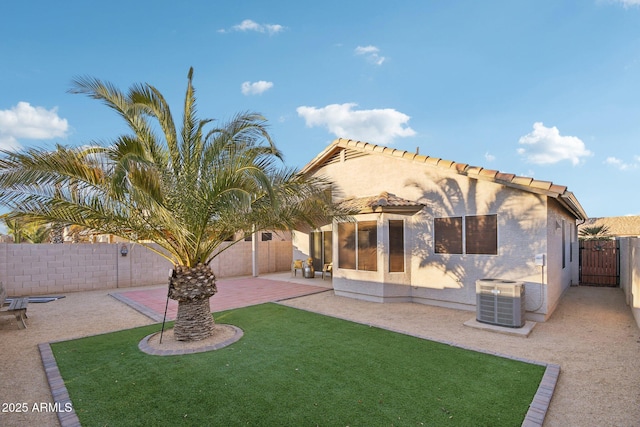 rear view of property featuring a lawn, cooling unit, and a patio area