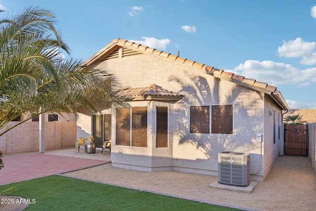 back of property with central AC and a patio