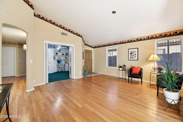 sitting room featuring vaulted ceiling, built in features, and hardwood / wood-style floors