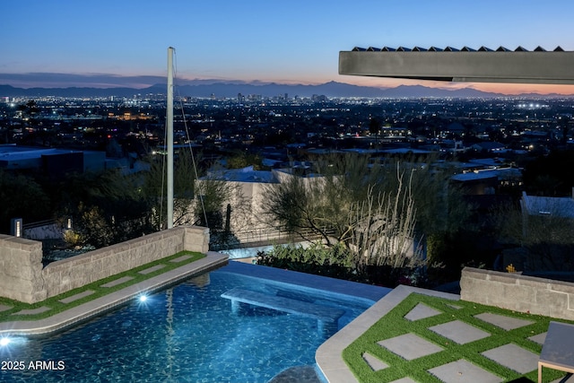 pool at dusk featuring a patio area and a mountain view