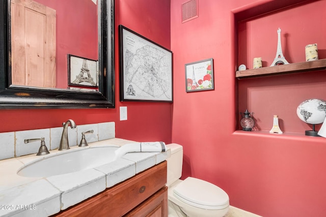 half bathroom with vanity, toilet, and visible vents