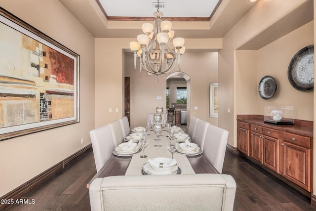 dining area featuring baseboards, a raised ceiling, arched walkways, and dark wood-style floors