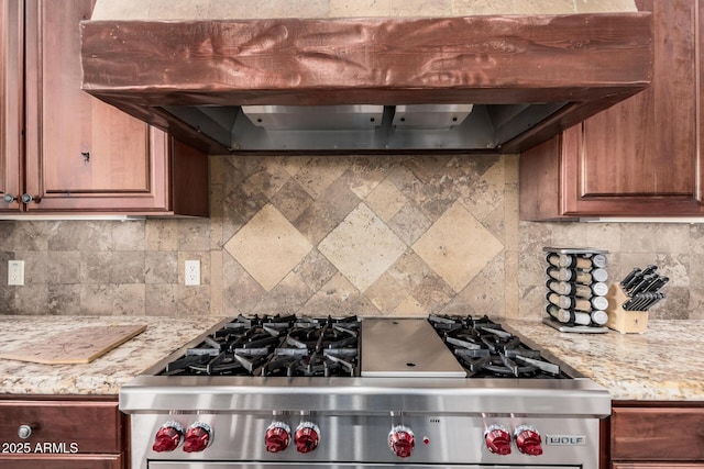 kitchen featuring backsplash, stainless steel range, light stone countertops, and premium range hood