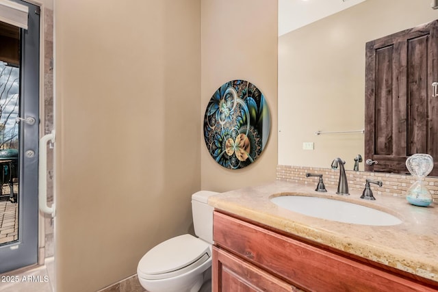 bathroom featuring vanity, toilet, and backsplash