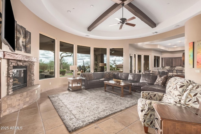 tiled living area with beam ceiling, visible vents, a fireplace, and a ceiling fan