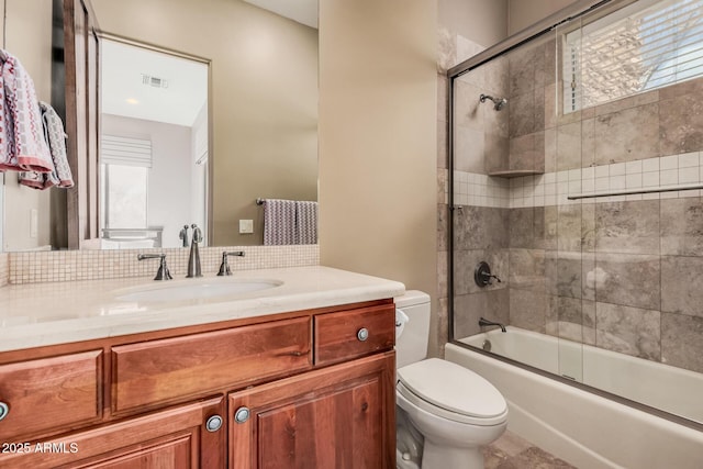 bathroom with vanity, toilet, visible vents, and enclosed tub / shower combo