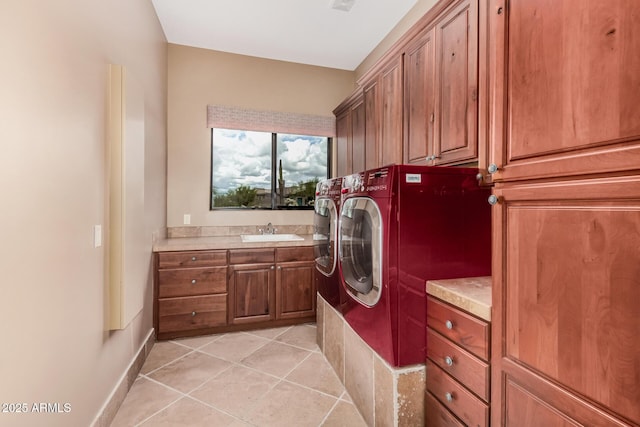 washroom with light tile patterned floors, baseboards, cabinet space, a sink, and washer and dryer