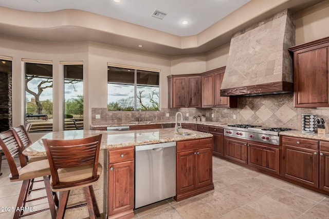 kitchen featuring visible vents, premium range hood, a sink, stainless steel appliances, and tasteful backsplash