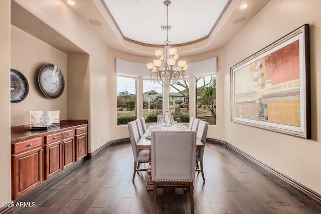 dining room featuring a tray ceiling, baseboards, dark wood-type flooring, and a notable chandelier