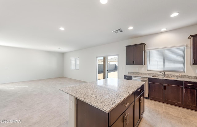 4993 S 254th Dr, Buckeye, AZ 85326 - kitchen with a sink, dishwasher, dark brown cabinetry, a kitchen island, and light stone counters
