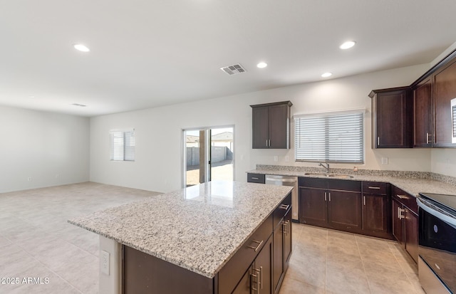 4993 S 254th Dr, Buckeye, AZ 85326 - kitchen with stainless steel appliances, a sink, dark brown cabinetry, a kitchen island, and light stone countertops