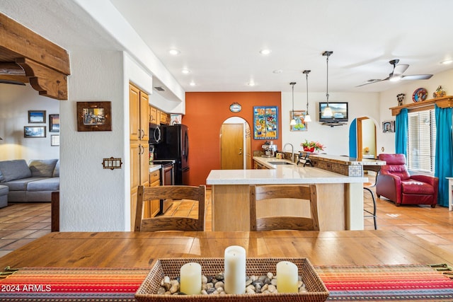 tiled dining space with ceiling fan and sink