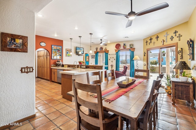 tiled dining room with ceiling fan and sink