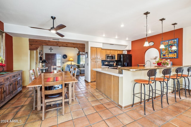 kitchen featuring pendant lighting, a breakfast bar, ceiling fan, appliances with stainless steel finishes, and light stone counters