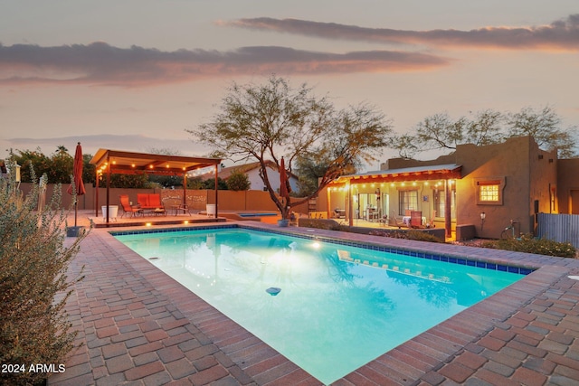 pool at dusk featuring a patio area and an outdoor living space