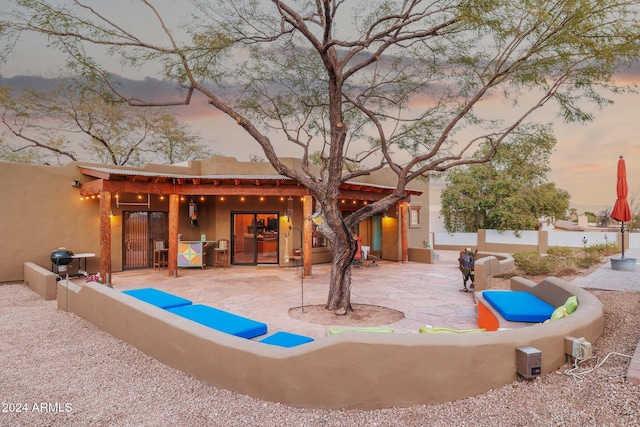 back house at dusk featuring a patio area