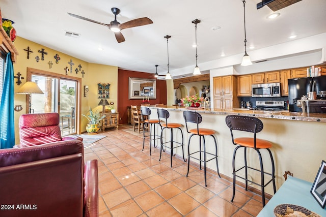 kitchen with a kitchen breakfast bar, tasteful backsplash, pendant lighting, black refrigerator, and range