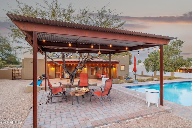 pool at dusk featuring a patio