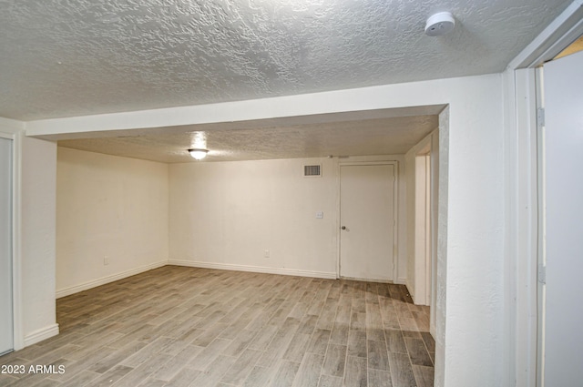 basement with light hardwood / wood-style flooring and a textured ceiling