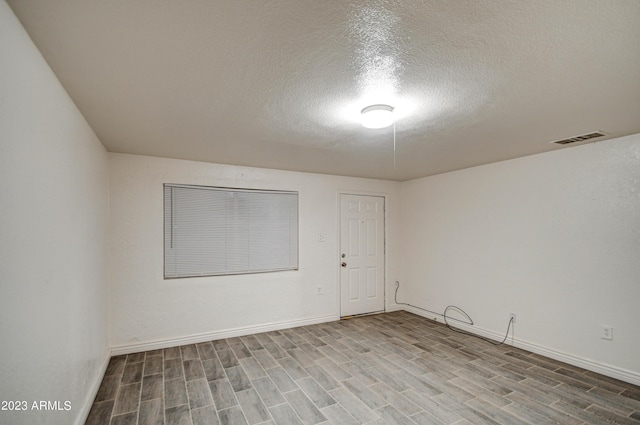 empty room featuring wood-type flooring and a textured ceiling