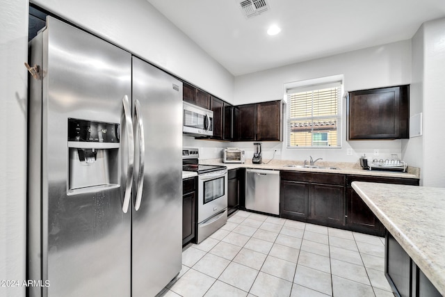 kitchen with dark brown cabinets, light tile patterned flooring, sink, and appliances with stainless steel finishes