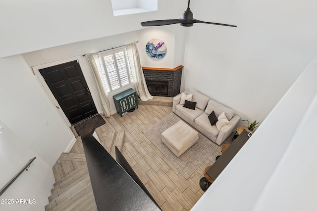 living room featuring ceiling fan, light parquet flooring, and a fireplace