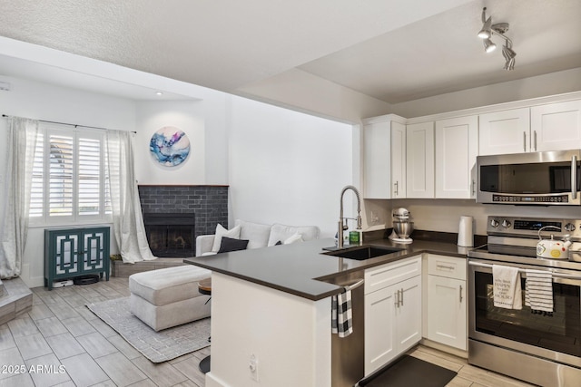 kitchen with sink, kitchen peninsula, white cabinets, and appliances with stainless steel finishes