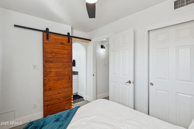 bedroom with ceiling fan, a barn door, and a closet