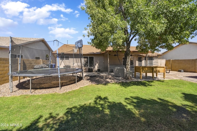 rear view of house with a yard, a deck, and a trampoline