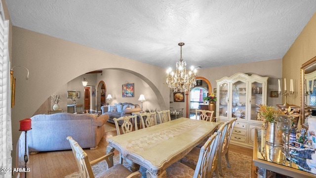 426 E Carol Ann Way, Phoenix, AZ 85022 - dining space with arched walkways, a chandelier, wood finished floors, and a textured ceiling