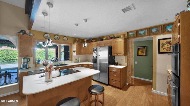 426 E Carol Ann Way, Phoenix, AZ 85022 - kitchen with black appliances, light countertops, light wood-type flooring, a kitchen island, and a textured ceiling