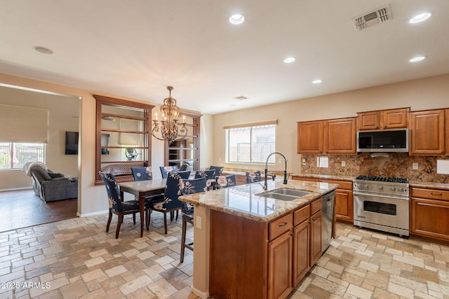 7169 S Dodane Ct, Gilbert, AZ 85298 - kitchen with stainless steel appliances, a sink, a chandelier, brown cabinetry, and tasteful backsplash