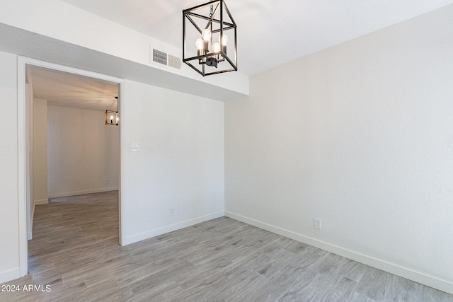 unfurnished room featuring an inviting chandelier and light hardwood / wood-style floors