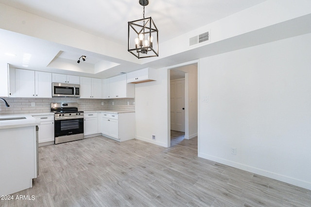 kitchen with white cabinets, hanging light fixtures, light wood-type flooring, stainless steel appliances, and a chandelier