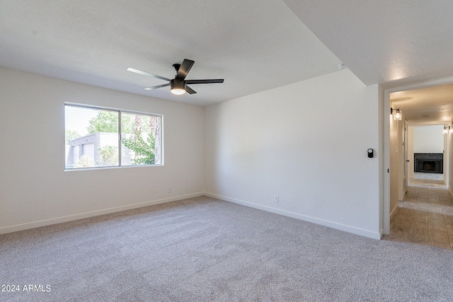 carpeted spare room with a textured ceiling and ceiling fan