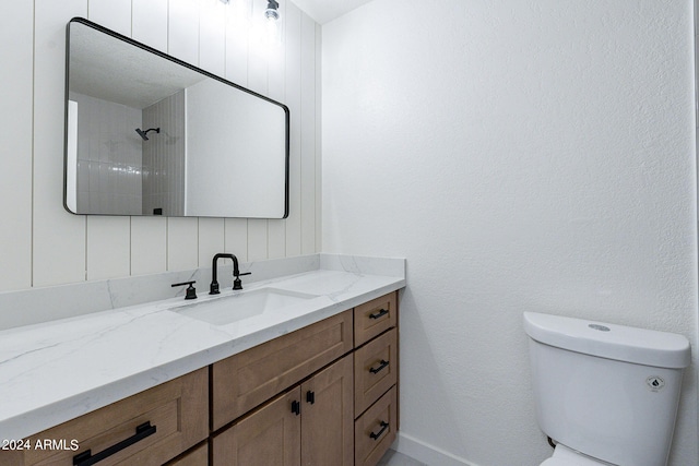 bathroom featuring tiled shower, vanity, and toilet