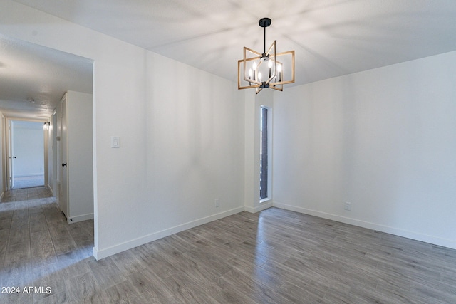 spare room with a notable chandelier and hardwood / wood-style floors