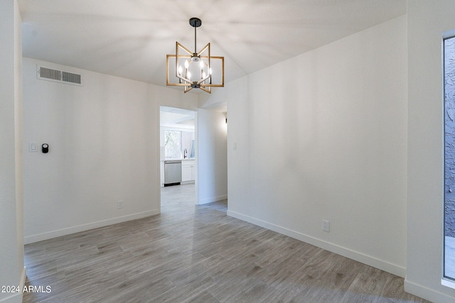 unfurnished dining area with light wood-type flooring, a chandelier, and sink