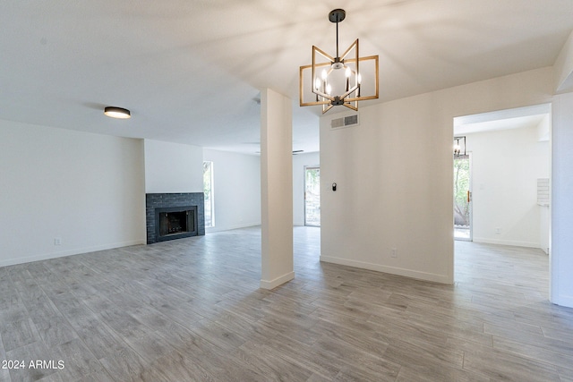 unfurnished living room featuring hardwood / wood-style floors, a fireplace, and a chandelier