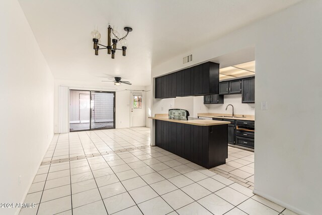 kitchen featuring ceiling fan, sink, kitchen peninsula, a breakfast bar area, and light tile patterned flooring