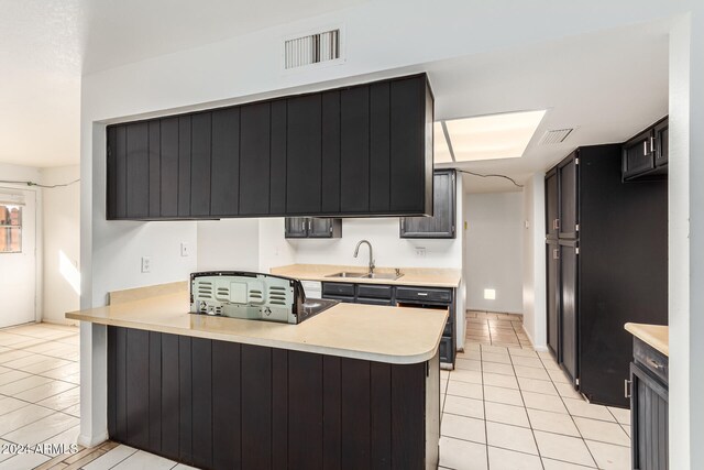 kitchen featuring kitchen peninsula, sink, and light tile patterned floors